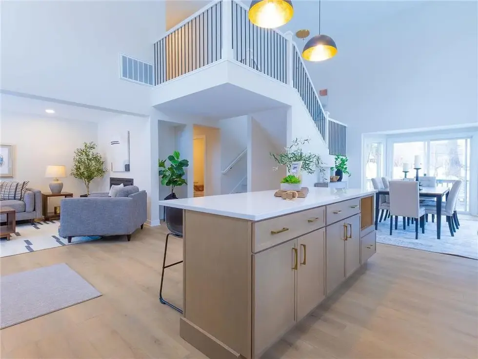 The view of the kitchen looking at the kitchen island, living room, dining and open staircase