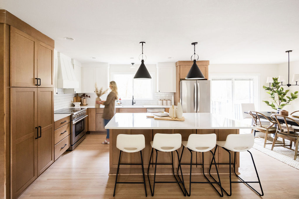 Modern kitchen with wood cabinets, white island, and black pendant lights