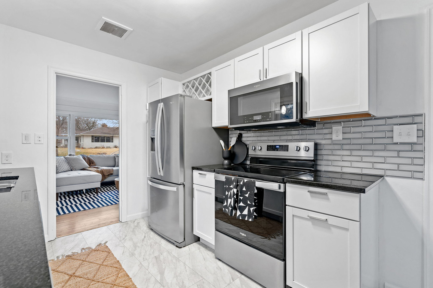 White kitchen with stainless steel appliances and living room view