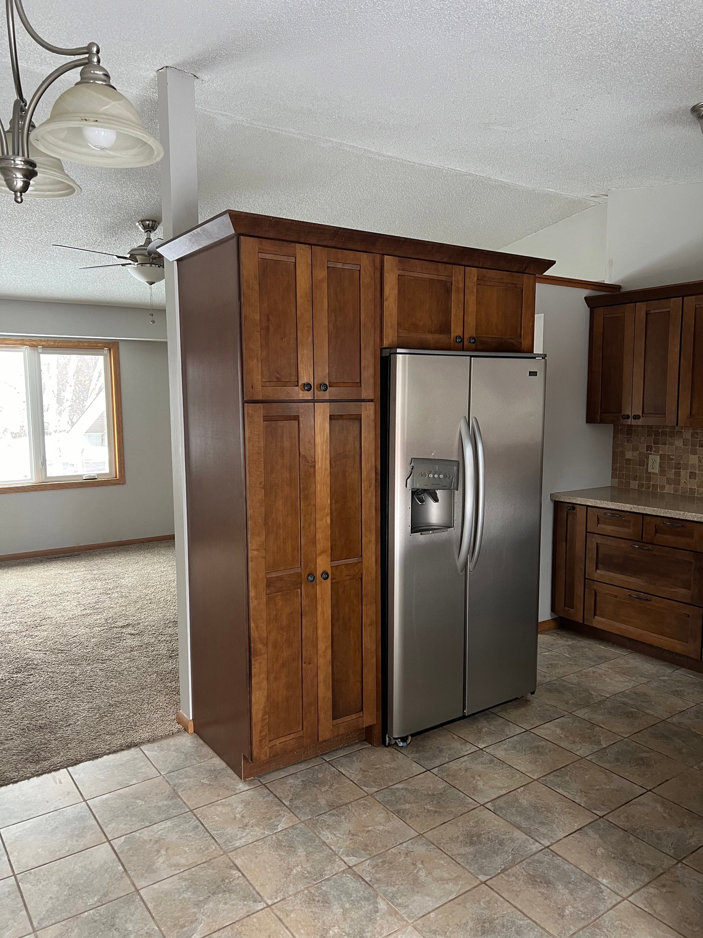 Wooden pantry and stainless steel refrigerator in kitchen