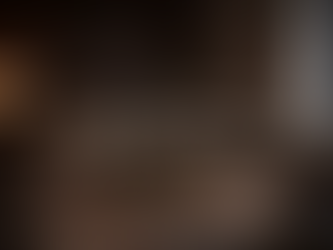 Dark luxury living room with taupe sectional sofa, brass round coffee table, architectural wood panel wall and abstract neutral rug