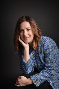 Professional head shot in a standard, traditional position of a brunette woman against a black background. Key West photography studio.