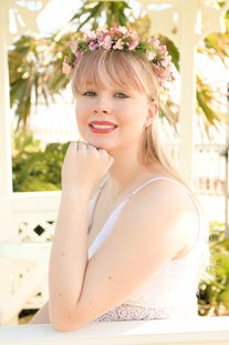Senior portrait of a blonde girl in a white dress wearing a flower crown in a white gazebo. Key West senior photos.