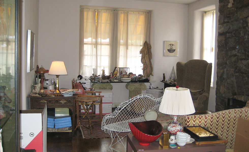 A cluttered living room being used as a staging area for sorting household belongings prior to staging