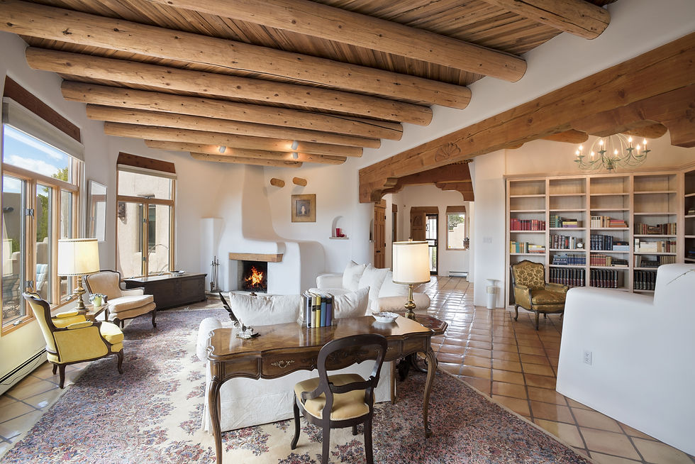 Formal Santa Fe living room with desert views, wood vigas, and library area staged for real estate photos.