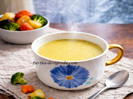 Parująca zupa krem z pieczonych warzyw w misce z namalowanym niebieskim kwiatem , podana z łyżką i gotowanymi warzywami w zimowym tle.