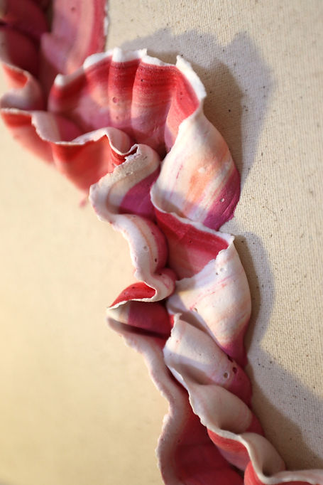 Abstract red and white ruffled ceramic sculpture on a wall