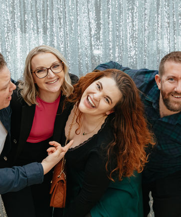 Smiling group at an event with a silver tinsel backdrop.