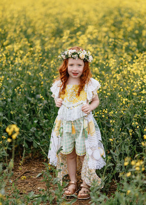 Young redhead girl in a flower crown in a yellow field.