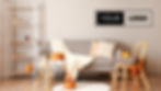 Cozy living room with a gray sofa, pumpkins on a white table, orange cushions, a wicker chair, and a sign reading "YOUR LOGO" on the wall.