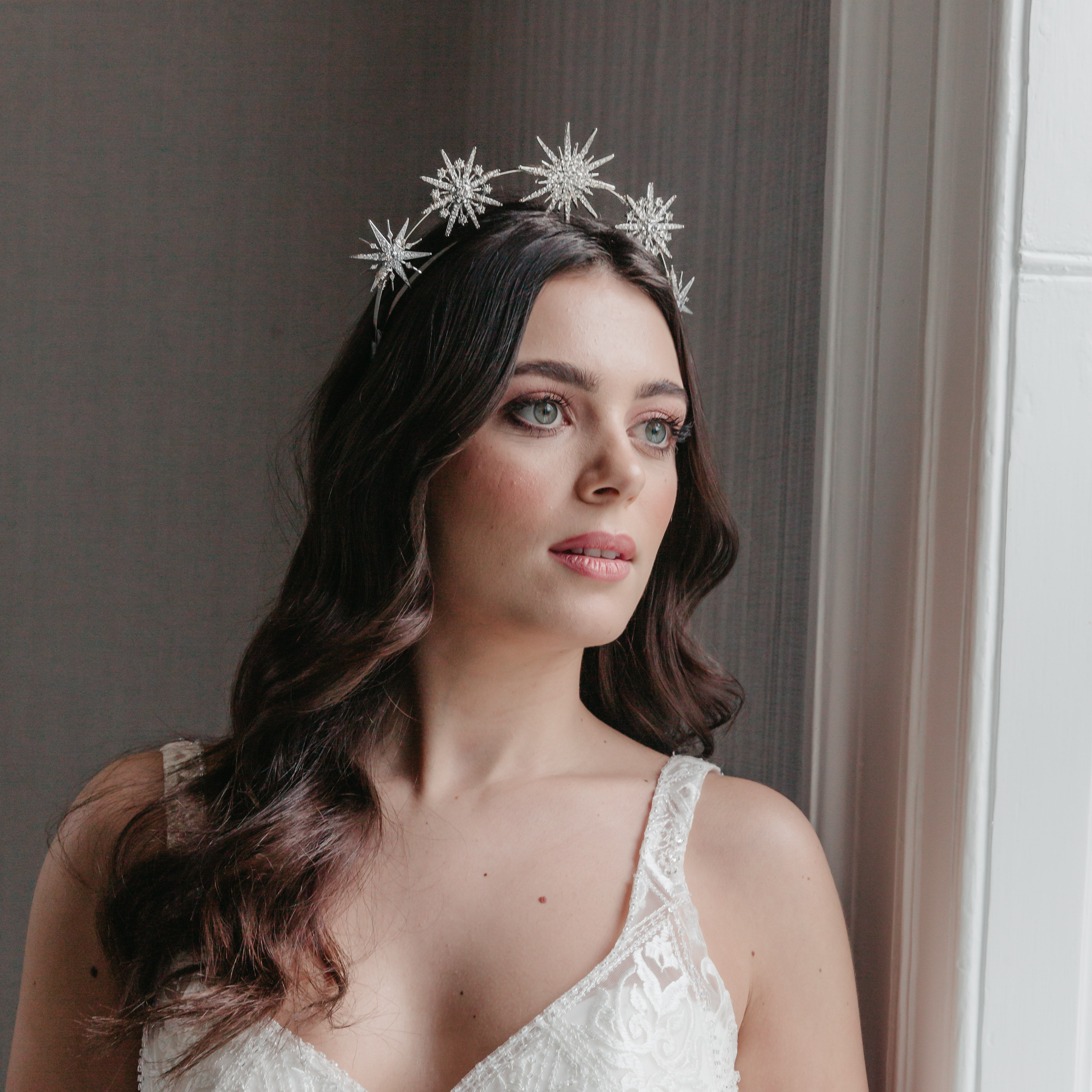 Bride wears silver celestial halo headpiece with sparkling crystal stars, perfect for a starry bridal look.