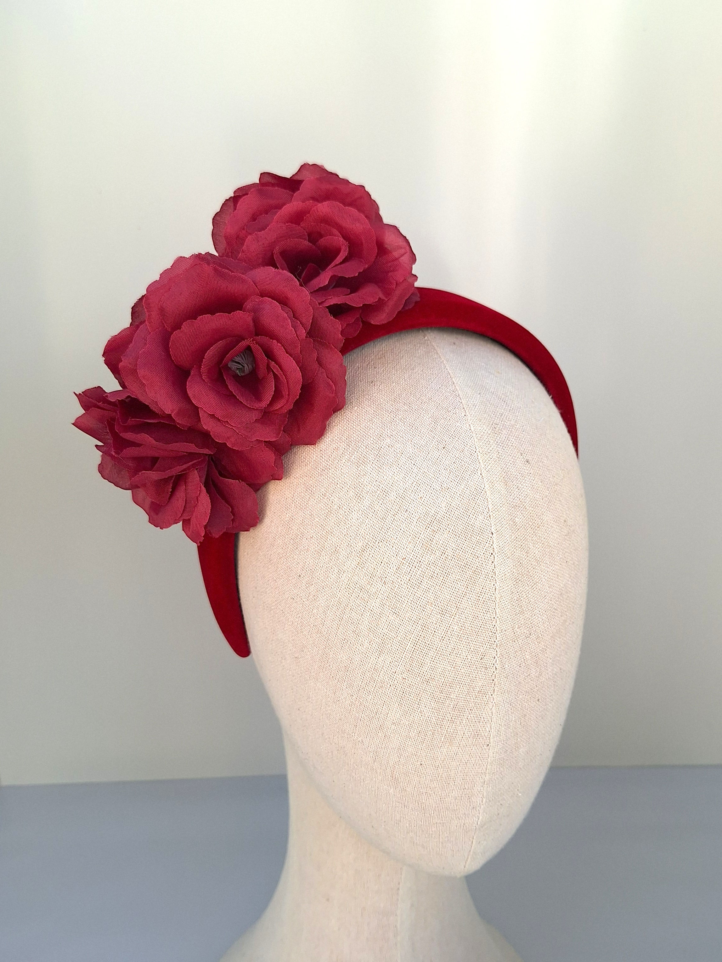Burgundy red silk rose fascinator on a mannequin, a stylish floral headpiece perfect for weddings and race day events