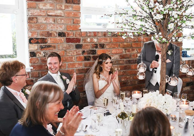 Happy wedding couple clapping during speeches