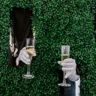 Champagne service passed through a hedge wall as a luxury guest experience detail