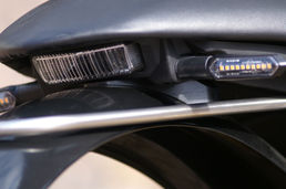 Motorrad Heckteil mit gelben Blinkern und schwarzem Nummernschildhalter Nahaufnahme.