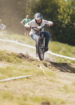 Mountainbiker fährt einen Hügel hinunter, Staub aufwirbelnd. Cippito E MTB Team.