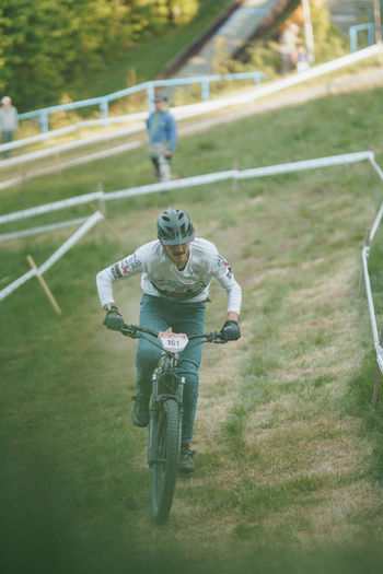 Mountainbiker fährt einen Hügel hinauf, grünes Gras, Wettrennen, weißes Band, Person beobachtet.