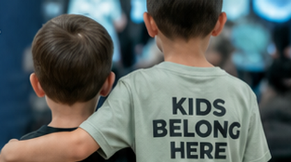 Photo of back of two children wearing a shirt that reads "kids belong here"