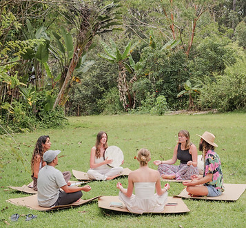 Small group sitting in a circle on the grass during a mindful ceremony at Hamakua Sanctuary on Hawaiʻi Island.
