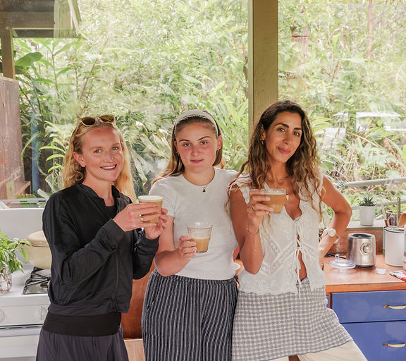 Volunteers smiling and sharing drinks in a tropical outdoor setting at Hamakua Sanctuary.