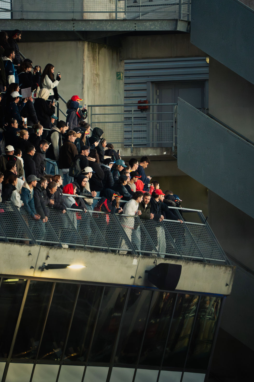Spectateurs rassemblés dans les tribunes d’un circuit automobile, observant la course sous une lumière chaude de fin d’après-midi.