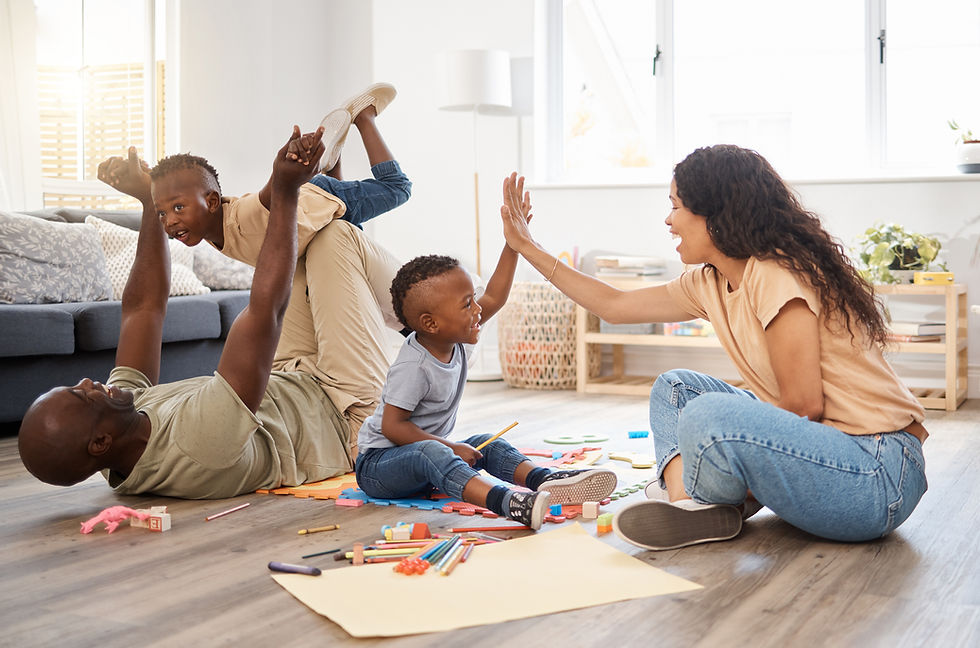Happy family playing on the living room floor, children high-fiving parents amid crayons and paper in a bright, cozy room