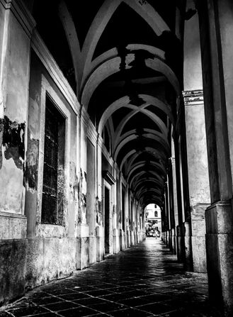 Classic sidewalk under arched roofs and pillars, tiles walkway - typical of Italian towns and cities, here Gaeta, Italy