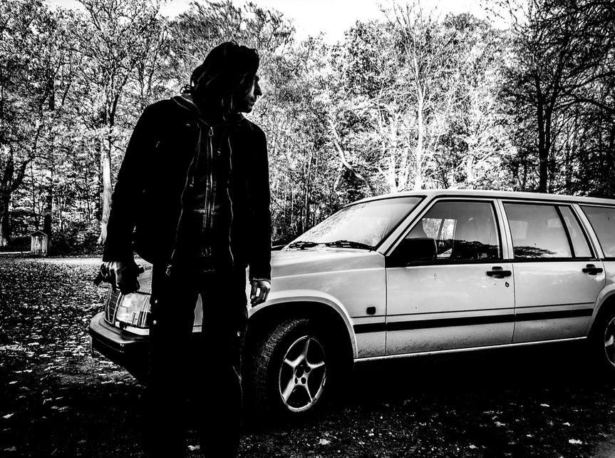 Man in front of classic Volvo, parked in the woods, Skaane, Sweden