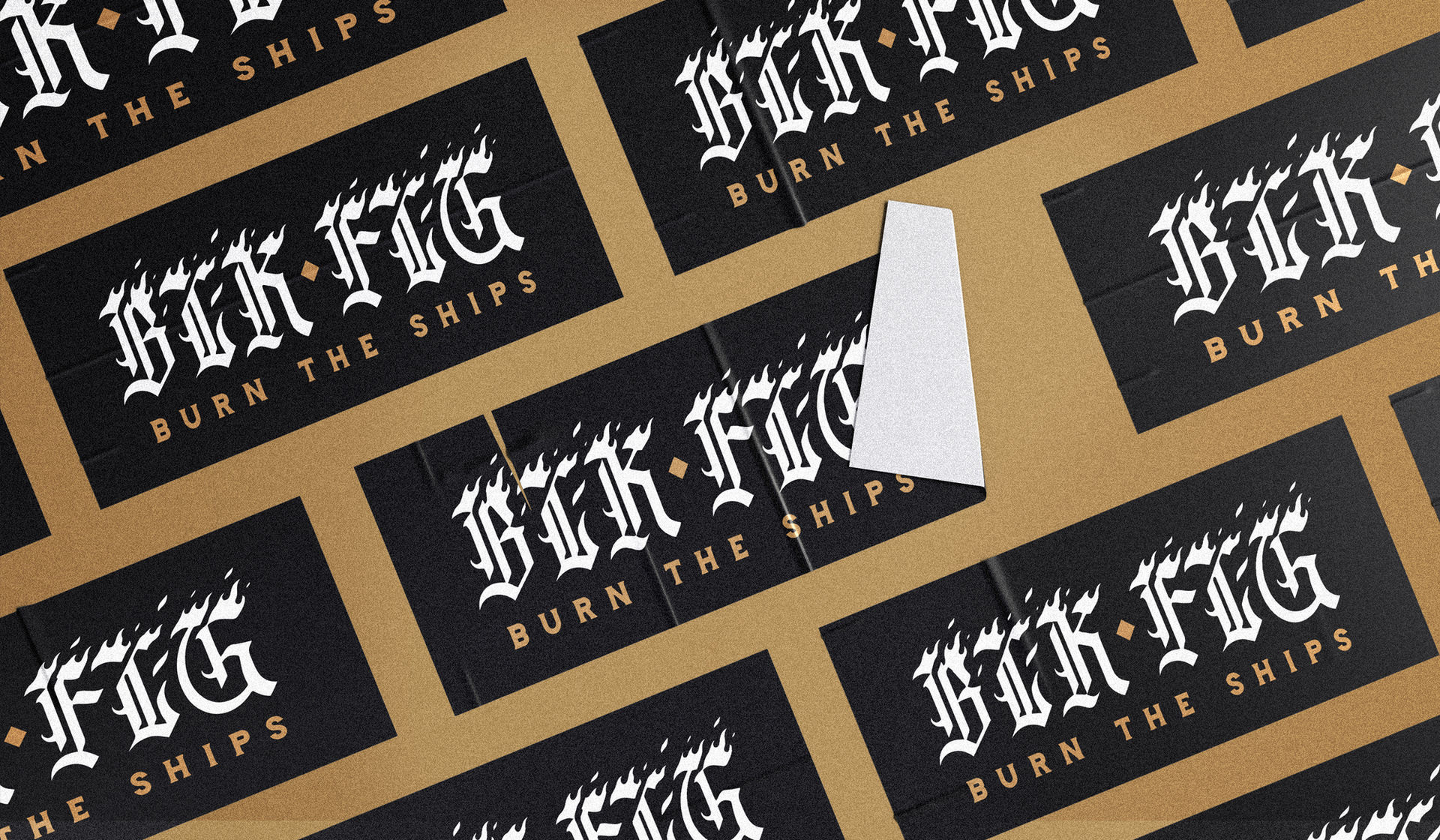 a gold wall with several stickers on it, one of the stickers is peeled. On the stickers is the text logo design saying BLK FLG in a gothic typeface, designed by freelance graphic designer, Stephen Williams