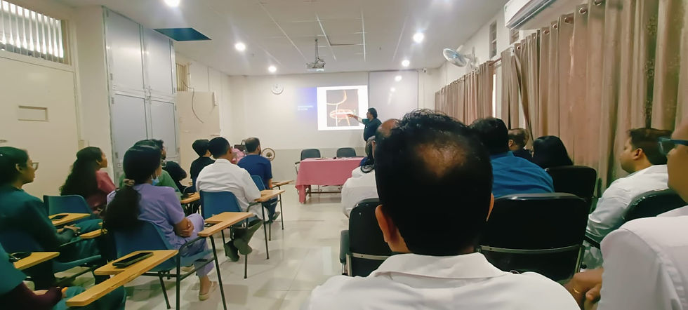 At RIMS Ranchi Audience listens to a presentation in a classroom with chairs and desks. Dr Debjyoti Dutta gestures at a projected slide. Curtains cover windows.