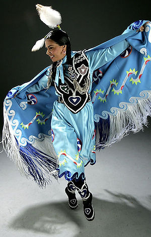a native woman dressed in light blue fancy shawl regalia