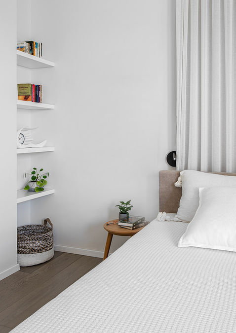 וילה בבצרהפינה בחדר השינה: עיצוב שקט עם סולם עץ דקורטיבי המשמש כמדף, שידת צד מעץ ומצעים לבנים נקיים.