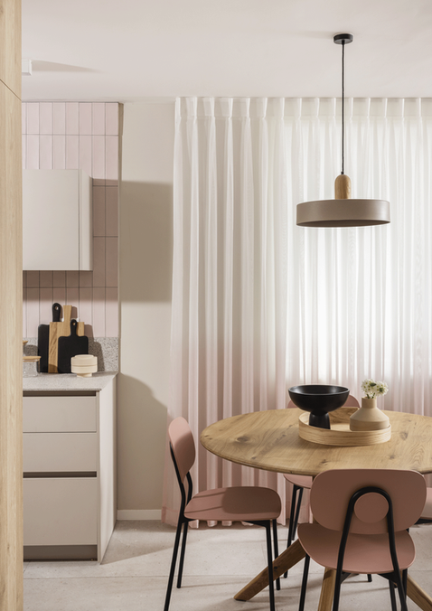 פנטהאוז בהרצליה - מבט חתוך פינת אוכל מעוצבת עם שולחן עץ עגול וכיסאות בגוון ורוד עתיק, לצד ארונות המטבח