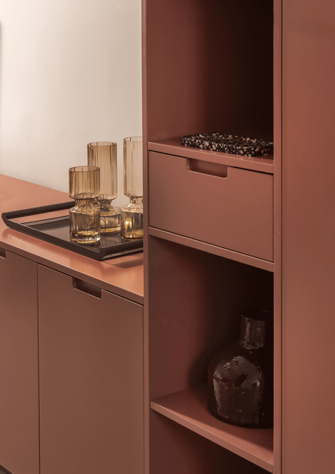 פנטהאוז בהרצליה - יחידת נגרות מותאמת אישית אנכית בגוון טרקוטה עמוק, המשלבת מגירות אחסון ומדפים פתוחים לאקססוריז מזכוכית.