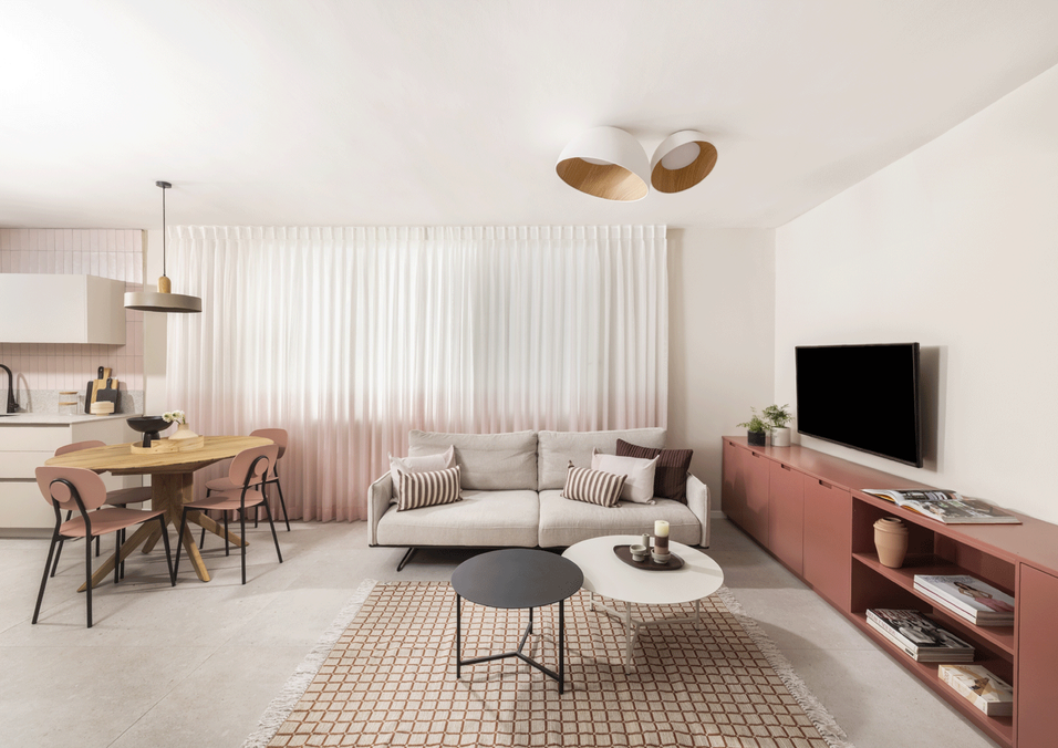 עיצוב פנטהאוז בהרצליה - סלון מודרני מואר בתכנון Open Space, הכולל מזנון נגרות אישית נמוך לאורך הקיר, שטיח מוגדר ופינת אוכל משפחתית.
