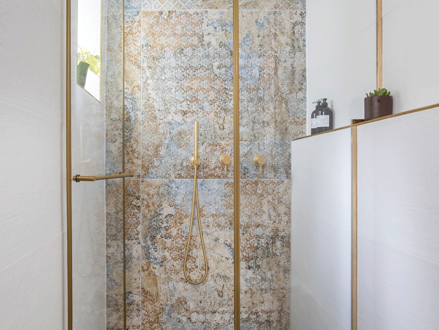 עיצוב דירה בראשון -מקלחון יוקרתי ומיוחד: שילוב של ריצוף שחמט גיאומטרי בשחור-לבן, חיפוי קיר בטקסטורת אבן פראית ופרזול זהב.