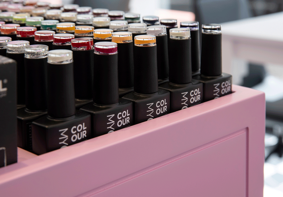 פתרונות תצוגה לעסקים: בקבוקי לק מסודרים בתוך מתקן נגרות ורוד ייעודי (Custom Made), המדגיש את הסדר והארגון במכון.