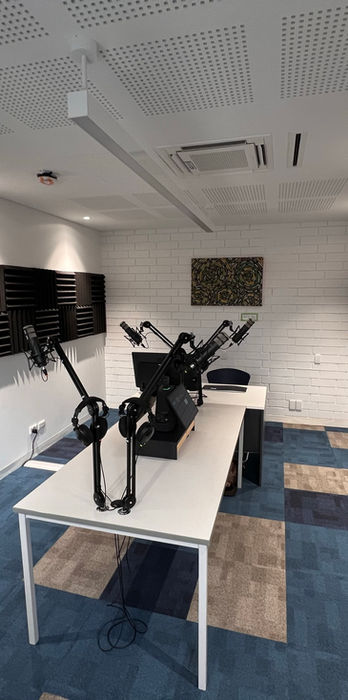 Long narrow corridor with wall-mounted display screens and rows of desks