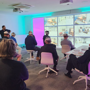 DATTASA members wearing VR headsets sit in a modern demonstration room at the Teach TEK office.