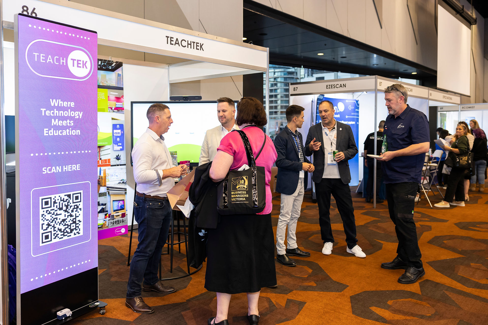 Attendees networking at the TEACHTEK booth during an education summit