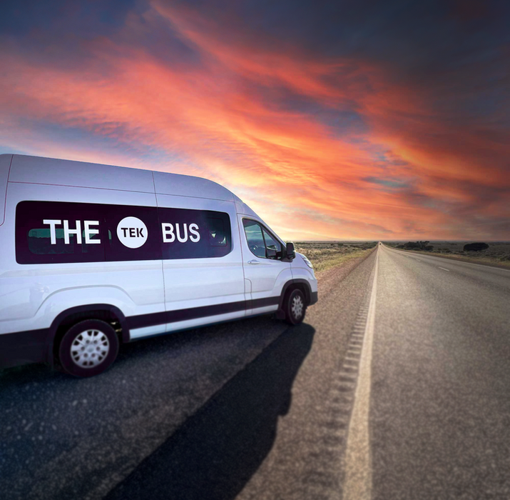 TeachTEK branded white van parked on an open road at sunset