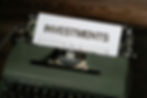 A vintage typewriter holds a sheet of paper boldly displaying the word "INVESTMENTS," symbolizing the importance of environmental investing.