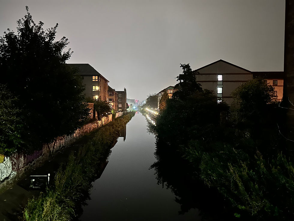 A grey overcast early evening over a still canal with a bike trail to the left. 
