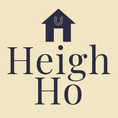 The Heigh Ho brand logo. A square shape with a wildflower cream background with the words Heigh Ho in midnight navy text in the centre. Above the brand name is a simple cottage logo featuring a horseshoe.
