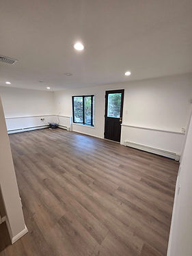 Room with new wood floor, white walls and dark door.