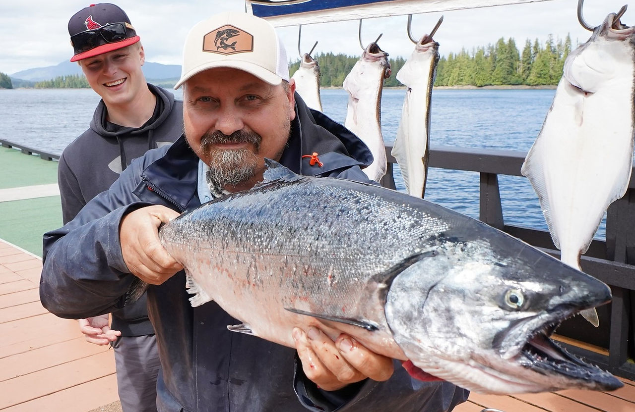 Captain Cliff holding up large salmon he caught while deep sea fishing in a cove in Alaska