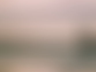 Silhouette of a person walking on a beach at sunset. Calm ocean waves and serene sky in background with reflection on wet sand.