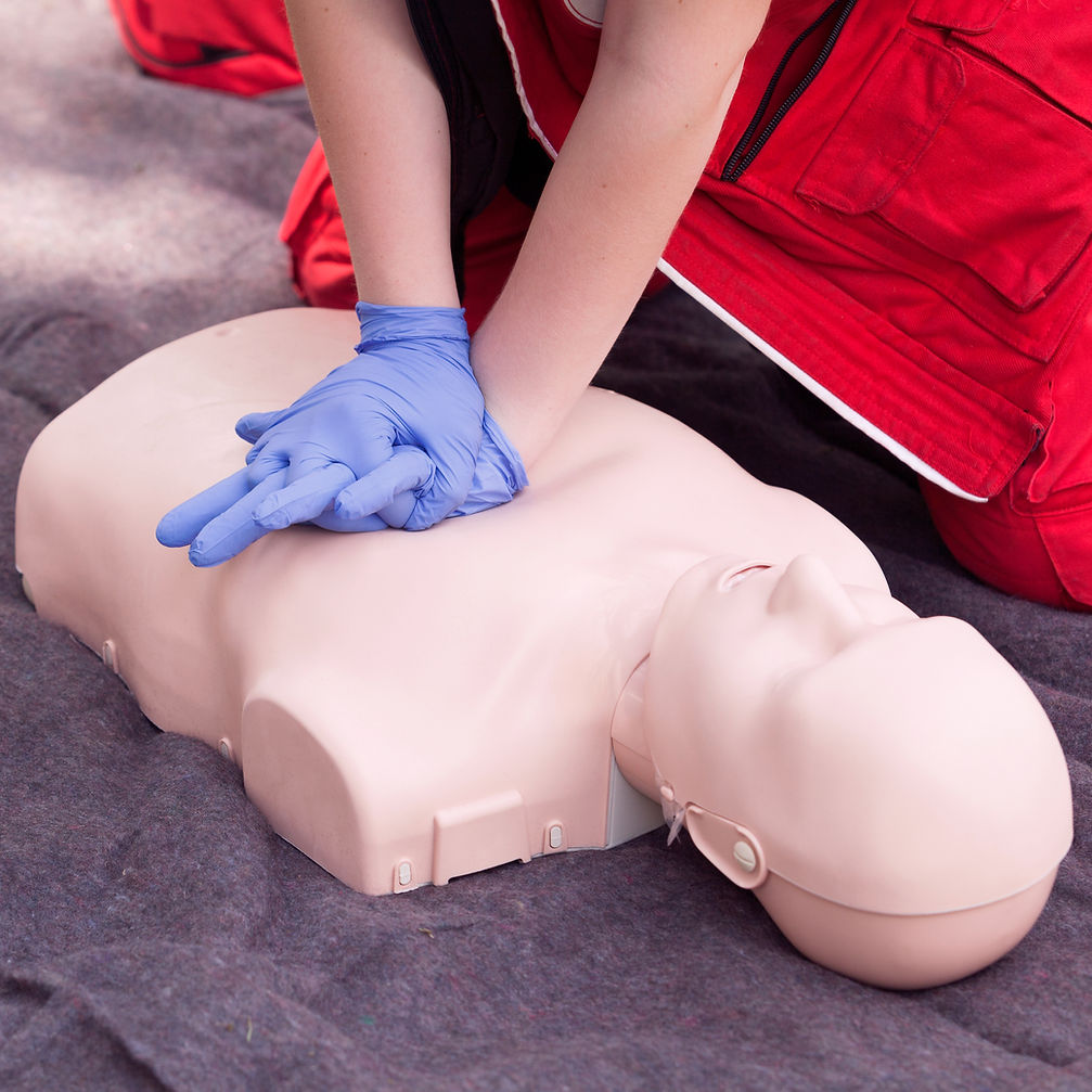 Person in red uniform performing CPR on a medical mannequin