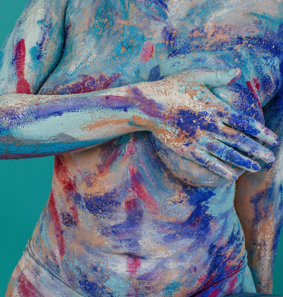 Woman with colorful body paint covering her torso, chest, shoulders, and arms, representing body awareness, identity, and self-expression.