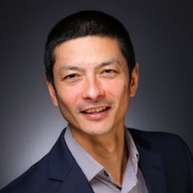 Image of William Nicholson, asian man looking at camera, he is wearing a suit, he is smiling and has short black hair